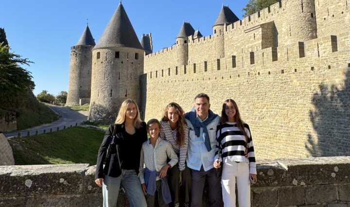 David y sus hijos frente a las murallas medievales de Carcassonne bajo un cielo azul.